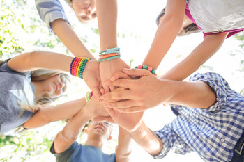 Jugendliche, die sich im Kreis stehend an die Hände fassen