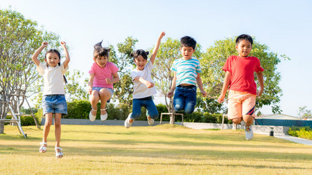 Kinder spielen im Freien und setzen gemeinsam zum Sprung an.