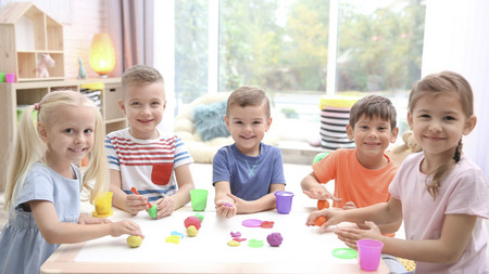 Kinder in einer Kita spielen am Tisch mit Bausteinen