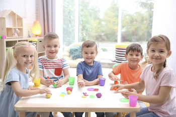 Kinder in einer Kita spielen am Tisch mit Bausteinen